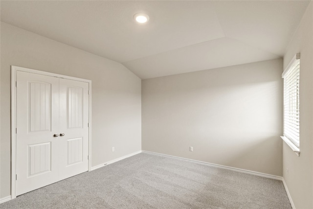 unfurnished room with light carpet and vaulted ceiling