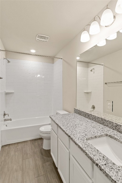 full bathroom with toilet, vanity, tiled shower / bath combo, and wood-type flooring