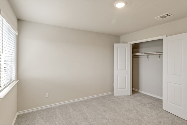 unfurnished bedroom featuring a closet, light colored carpet, and multiple windows