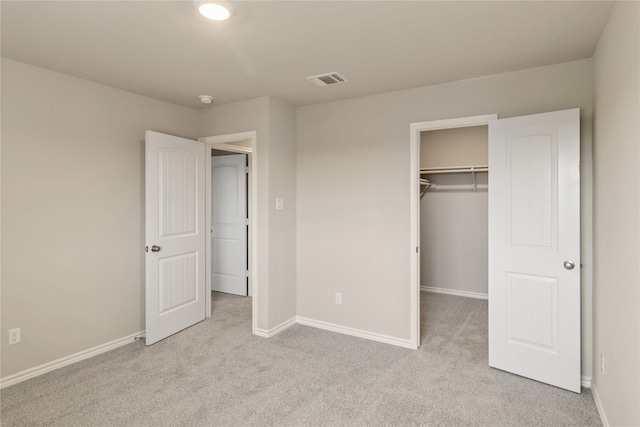 unfurnished bedroom featuring light carpet, a walk in closet, and a closet