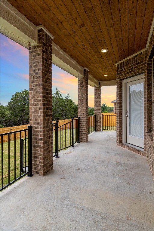 patio terrace at dusk featuring a lawn