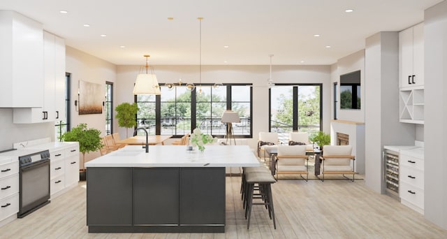 kitchen with a kitchen island with sink, a breakfast bar area, black range with electric cooktop, white cabinets, and pendant lighting