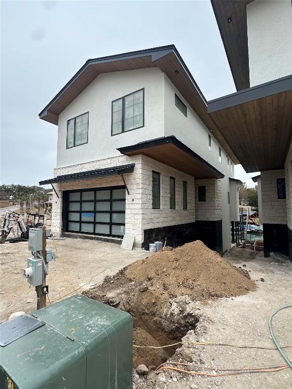 view of front of house with stone siding, concrete driveway, an attached garage, and stucco siding