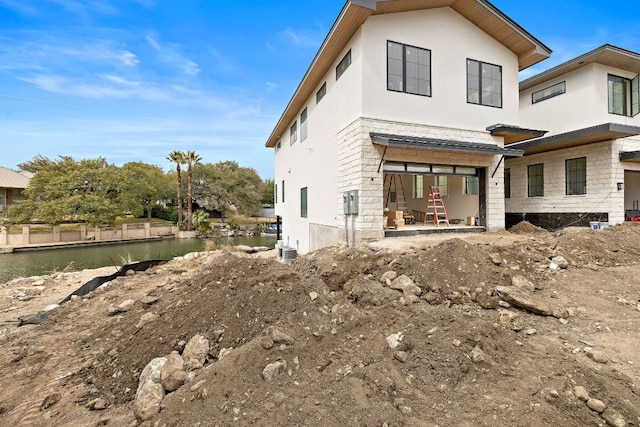 back of property featuring a water view and stucco siding