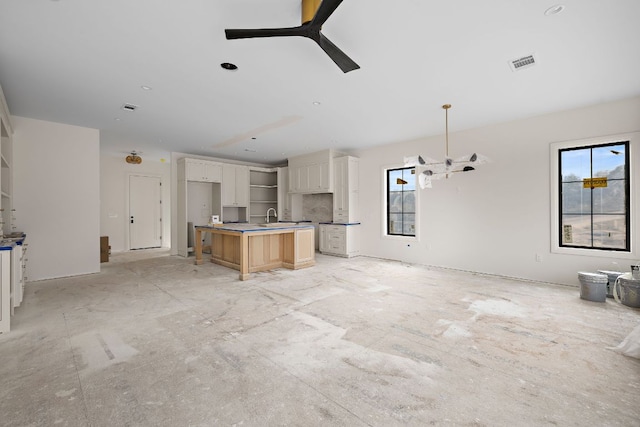 kitchen with a center island with sink, visible vents, open floor plan, ceiling fan, and a sink