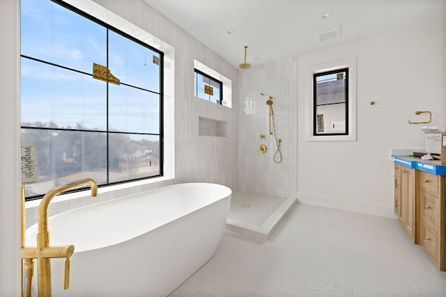 bathroom with baseboards, visible vents, tiled shower, a soaking tub, and vanity