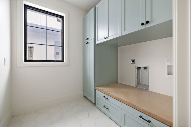 washroom featuring hookup for an electric dryer, cabinet space, and baseboards