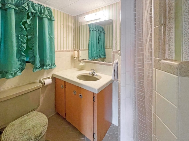 bathroom featuring toilet, tasteful backsplash, vanity, and tile walls