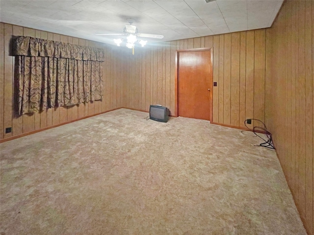 basement with light carpet, wooden walls, and ceiling fan