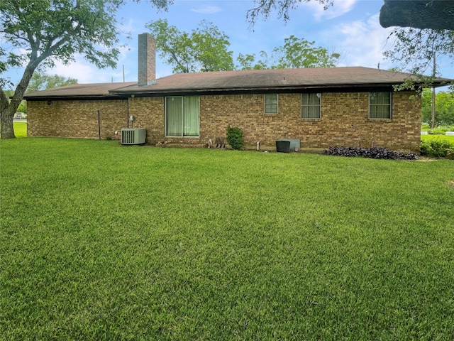 rear view of property with central AC unit and a yard