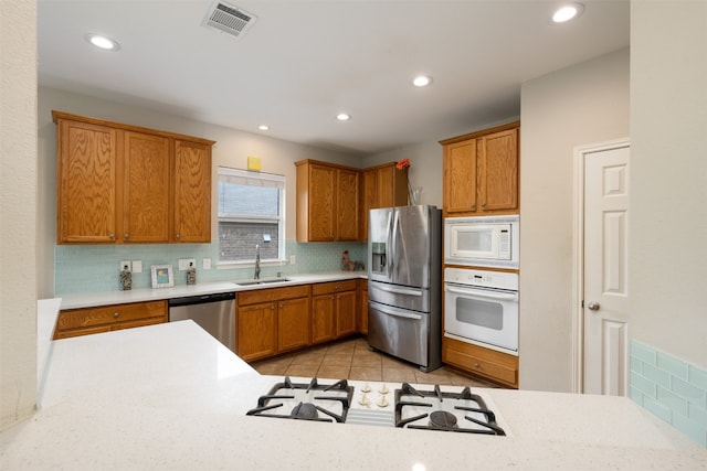 kitchen featuring light tile floors, backsplash, sink, and stainless steel appliances