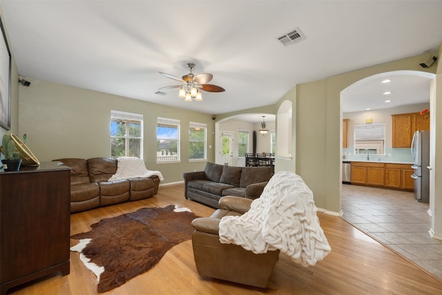 tiled living room with ceiling fan and sink