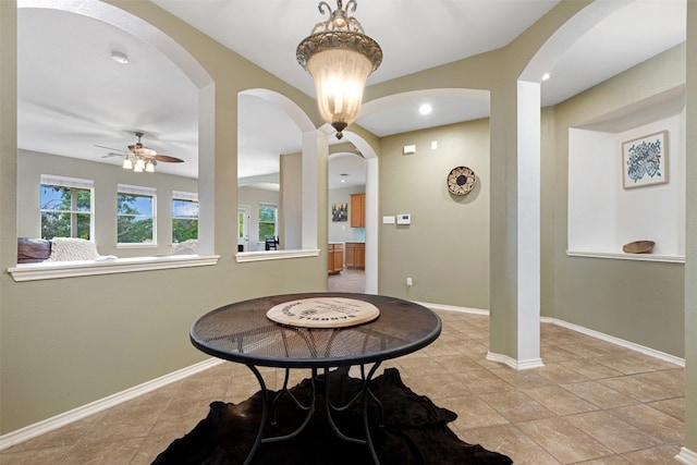 tiled dining area featuring ceiling fan with notable chandelier