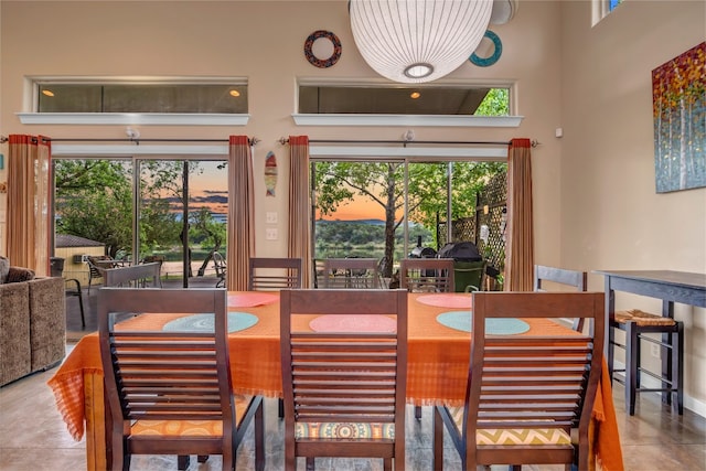 tiled dining space featuring plenty of natural light and a high ceiling