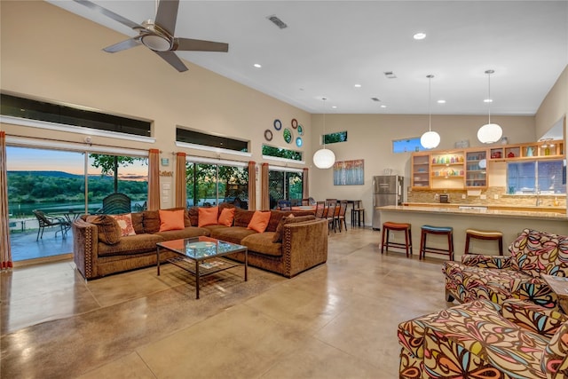 tiled living room with ceiling fan and high vaulted ceiling