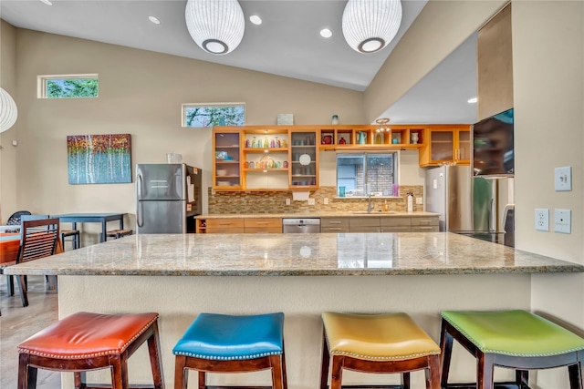 kitchen featuring backsplash, vaulted ceiling, appliances with stainless steel finishes, and a breakfast bar