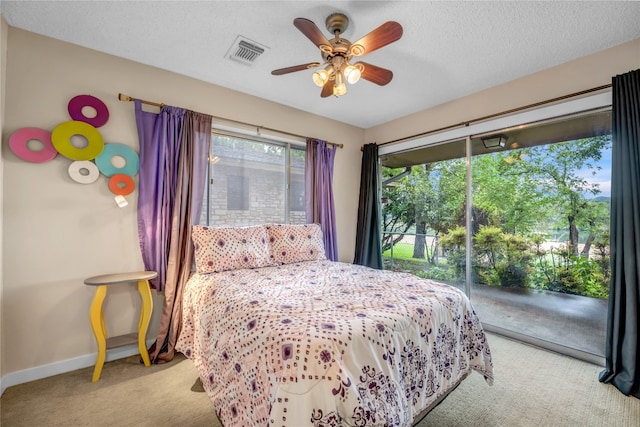 bedroom featuring ceiling fan, a textured ceiling, light colored carpet, and access to exterior