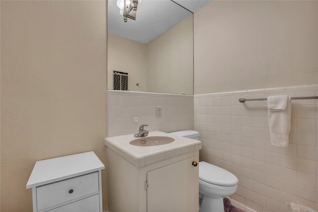 bathroom featuring vanity, backsplash, toilet, and tile walls