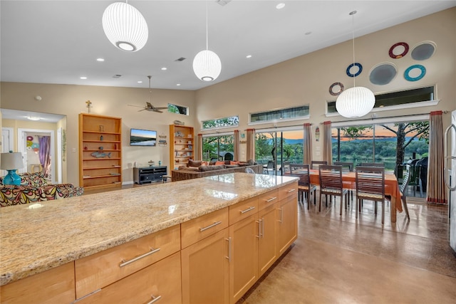 kitchen with light brown cabinets, high vaulted ceiling, ceiling fan, hanging light fixtures, and light stone counters