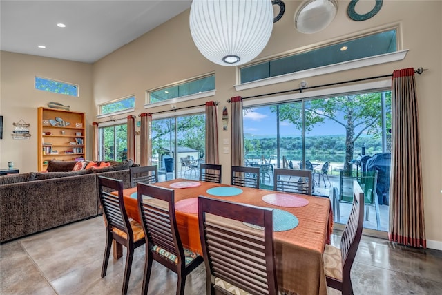 dining room with built in shelves, plenty of natural light, a high ceiling, and light tile floors