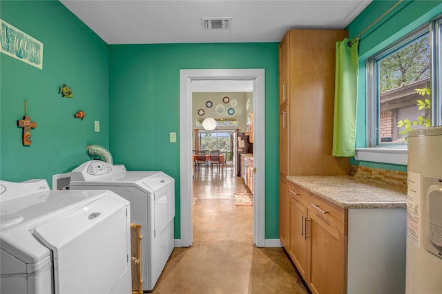 clothes washing area with electric water heater, a wealth of natural light, hookup for a washing machine, and washer and clothes dryer