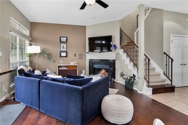 living room featuring dark tile flooring, a fireplace, and ceiling fan