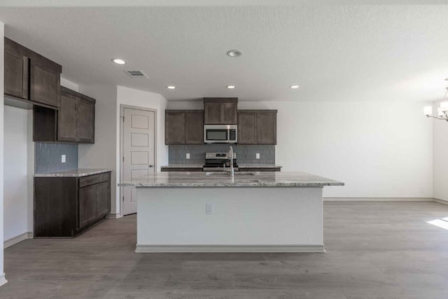 kitchen with an inviting chandelier, a center island with sink, and light hardwood / wood-style floors