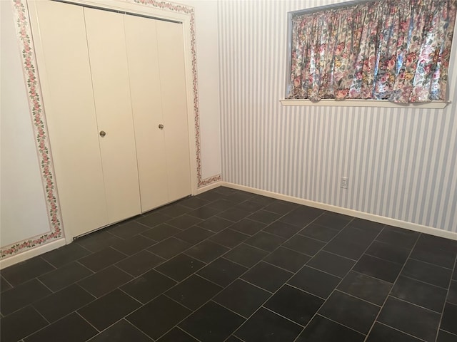 unfurnished bedroom featuring a closet and dark tile floors