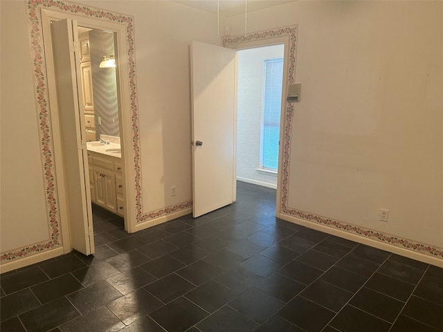 unfurnished bedroom with dark tile flooring and ensuite bath