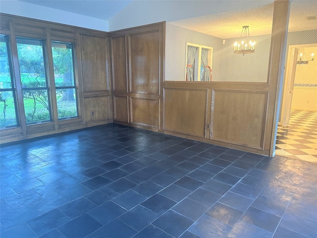 spare room with dark tile floors, a chandelier, and a textured ceiling