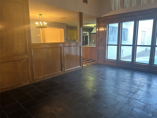 unfurnished living room featuring an inviting chandelier and dark tile floors