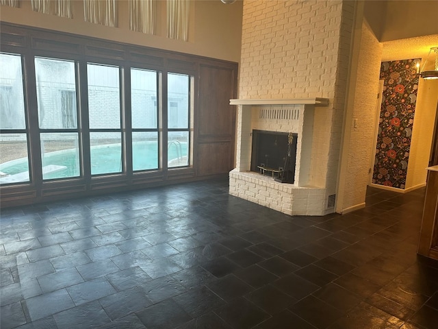 unfurnished living room featuring brick wall, dark tile floors, and a brick fireplace