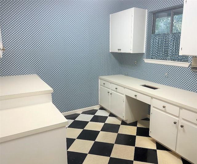 kitchen with white cabinets, built in desk, and light tile floors