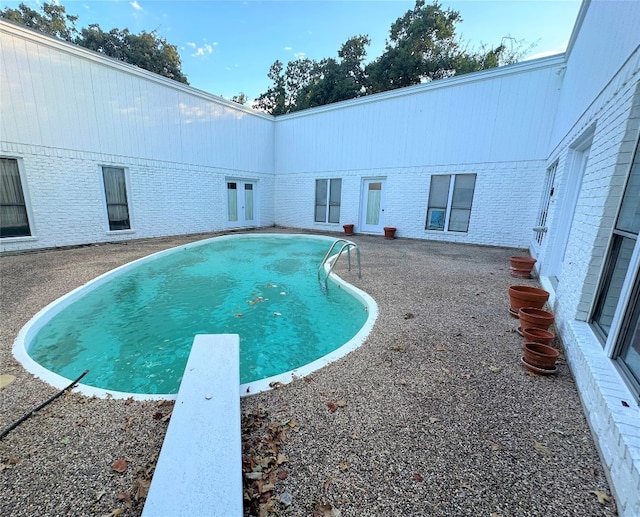 view of swimming pool featuring a diving board and a patio area