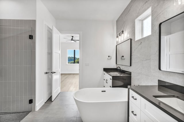 bathroom featuring tile walls, ceiling fan, vanity with extensive cabinet space, a bath, and hardwood / wood-style flooring