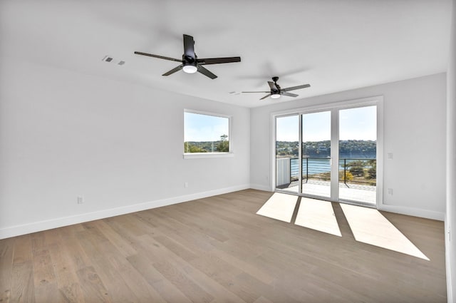 spare room featuring a water view, light hardwood / wood-style floors, and ceiling fan