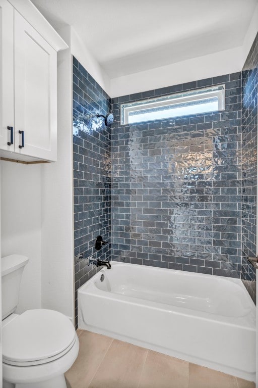 bathroom featuring tiled shower / bath combo, toilet, and tile flooring