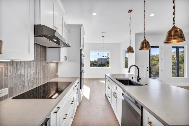 kitchen featuring stainless steel appliances, decorative light fixtures, backsplash, light wood-type flooring, and sink