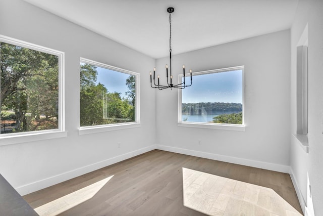 unfurnished dining area with dark wood-type flooring, a water view, and a chandelier