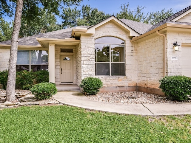 doorway to property featuring a garage and a lawn