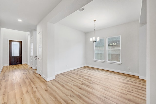 unfurnished room with an inviting chandelier and light hardwood / wood-style flooring