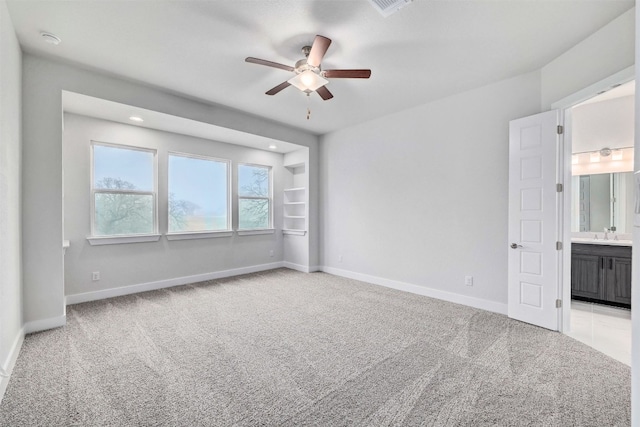 unfurnished bedroom featuring light carpet, ceiling fan, and ensuite bathroom