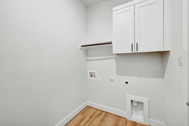 washroom featuring washer hookup, hookup for an electric dryer, gas dryer hookup, cabinets, and light wood-type flooring