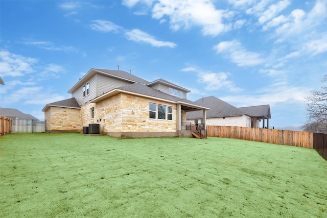 back of house with central air condition unit and a lawn