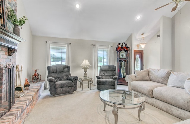 carpeted living room with ceiling fan, lofted ceiling, a brick fireplace, and plenty of natural light