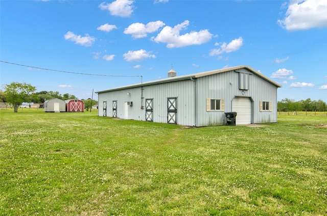 rear view of property with a garage, a yard, and an outdoor structure