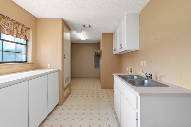 kitchen with sink, white cabinetry, a textured ceiling, and light tile flooring