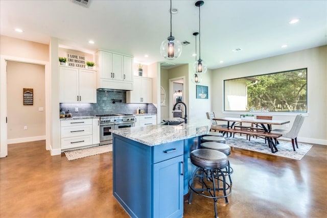 kitchen with pendant lighting, tasteful backsplash, a kitchen bar, white cabinetry, and range with two ovens