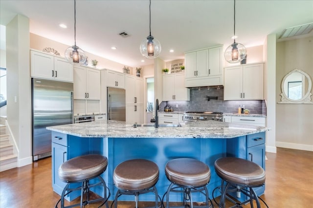 kitchen featuring built in fridge, high quality fridge, stove, white cabinetry, and hanging light fixtures