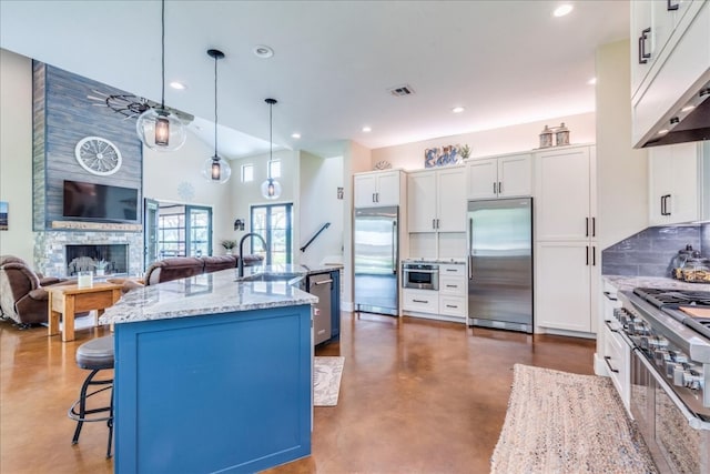 kitchen featuring decorative light fixtures, white cabinetry, a kitchen bar, and stainless steel appliances